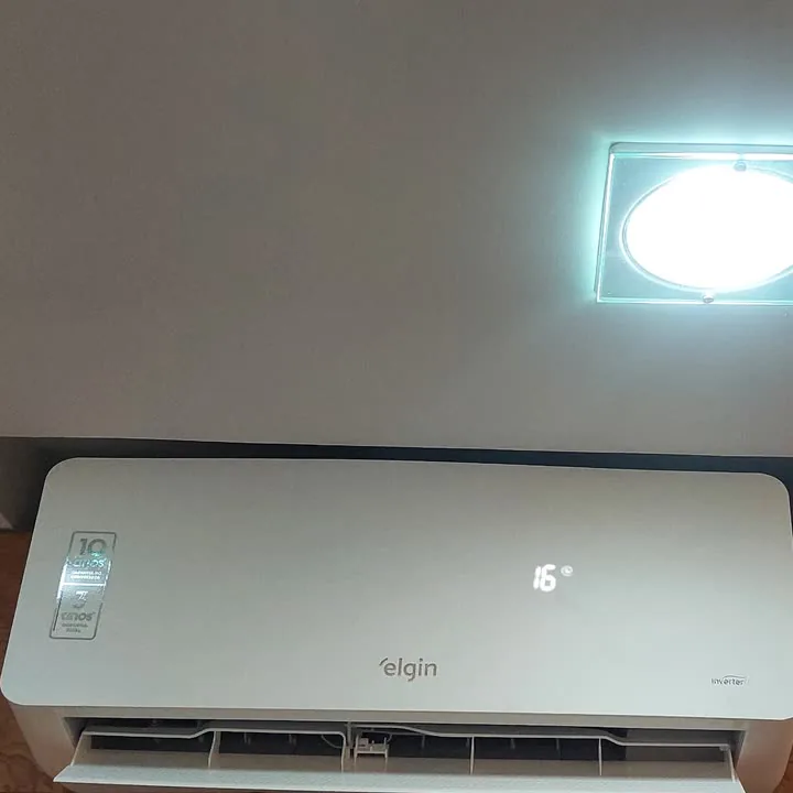 Ar-condicionado split instalado, ligado, abaixo de uma luminária